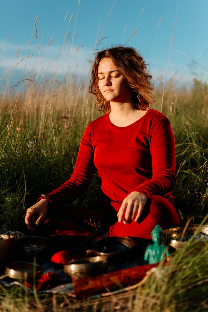 The Art of Drawing Readers In: Your attractive post title goes here Woman in red practicing meditation in a peaceful outdoor environment with grass and sunlight.