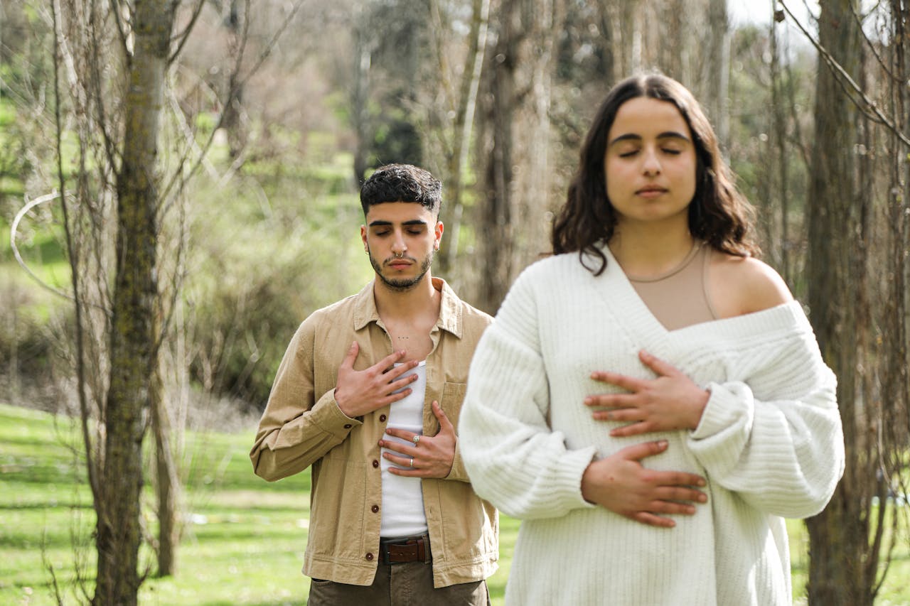service-01 A man and woman meditating with closed eyes, embodying peace and relaxation in a forest.